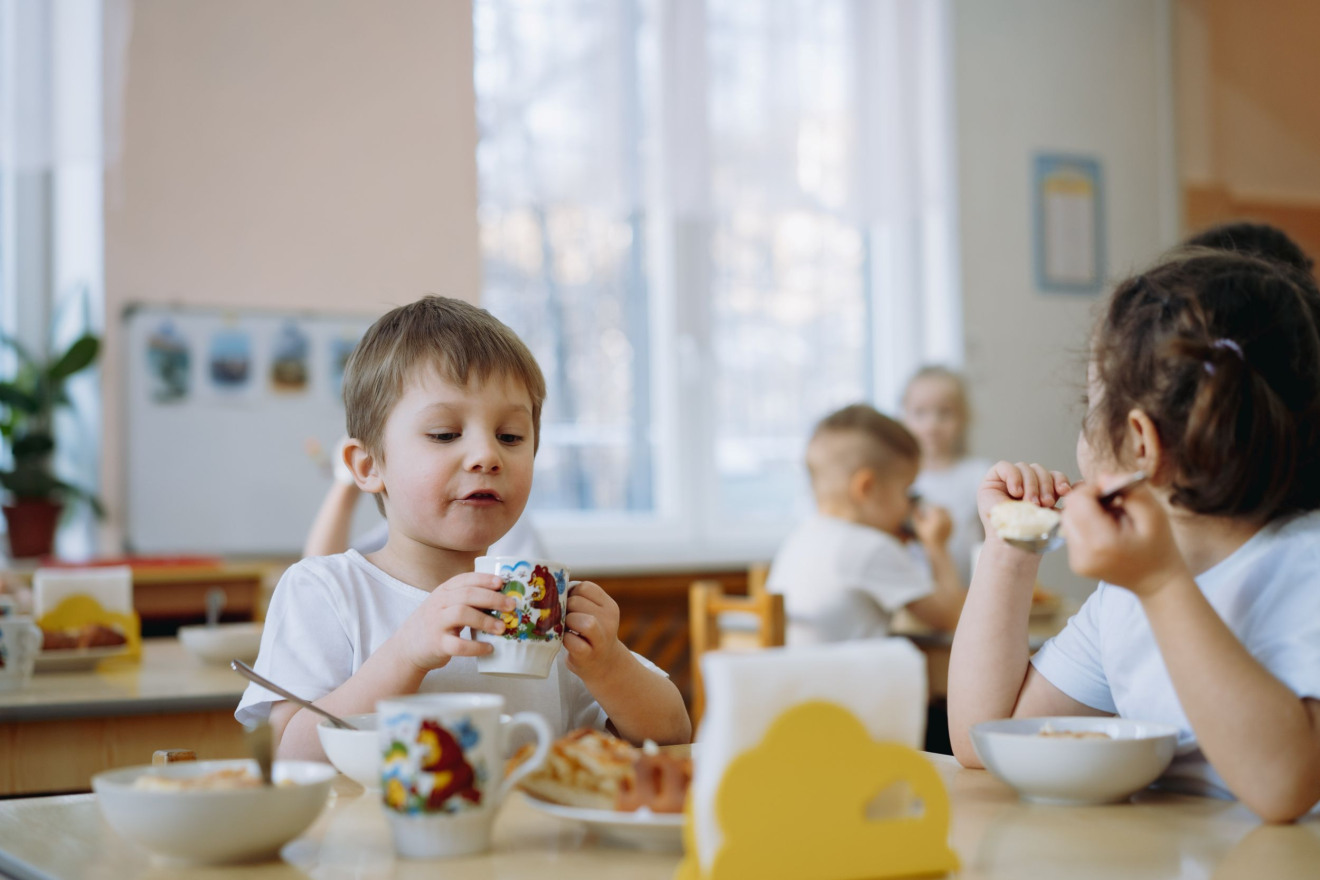Kinder sitzen am Mittagstisch und essen gemeinsam