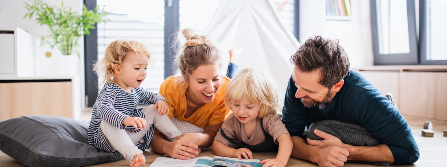 Eine Familie liest gemeinsam ein Buch auf dem Boden